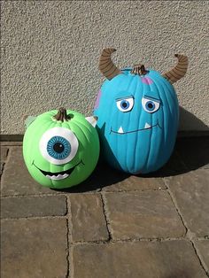 two pumpkins that have been decorated to look like monsters, one is blue and the other is green