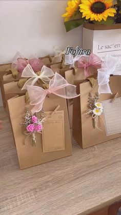 small brown bags with pink and white bows are on a table next to a sunflower