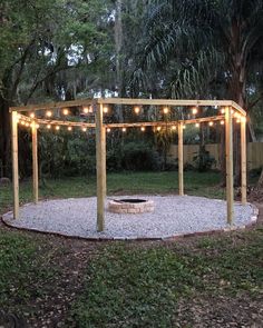 an outdoor fire pit with lights strung around it in the middle of a backyard area