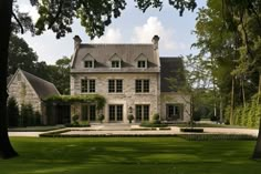 a large stone house surrounded by lush green grass and trees in front of the building