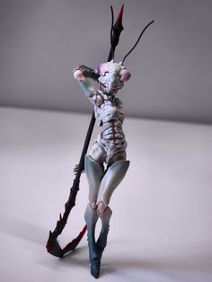 a white and black figurine holding a long stick with blood on it's legs