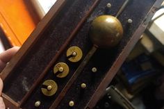 a person is holding an old wooden box with knobs and numbers on the side