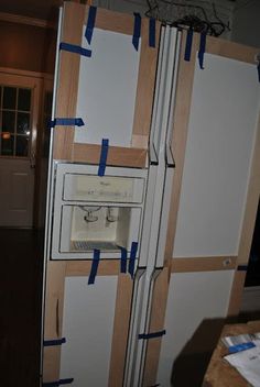 a refrigerator is taped up and ready to be built into the wall with blue tape on it