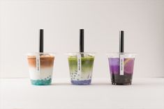 three different colored drinks with black straws