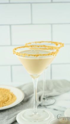 three glasses filled with yellow liquid on top of a marble table next to a white plate