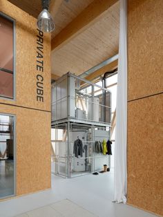 the inside of a building that is made out of plywood and has clothes hanging on it