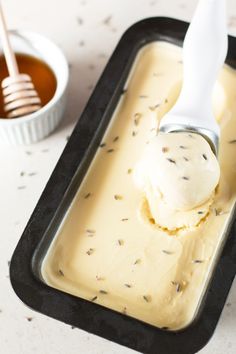 a scoop of vanilla ice cream in a black tray with a spoon next to it