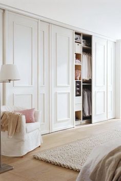 a bedroom with white closets and a bed in the corner next to a chair