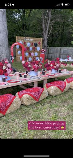 a table set up for a party with red and white decorations on top of hay bales