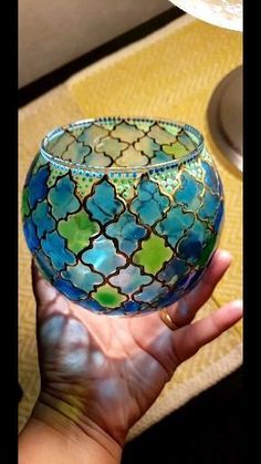 a hand holding a blue and green glass bowl