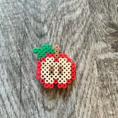 an apple made out of perler beads sitting on top of a wooden table,