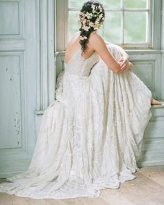 a woman in a wedding dress sitting on a window sill with her back to the camera