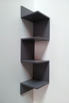 three black shelves on the wall with one empty shelf in front of them and another closed