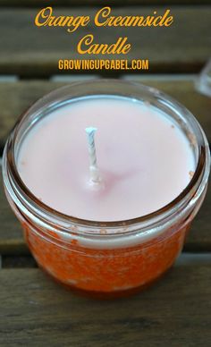 an orange creamsice candle in a glass jar on a wooden table with text overlay