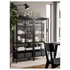 a black bookcase with glass doors and drawers in front of a dining room table