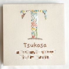 a cross stitched onto a canvas with the word tsukasa on it