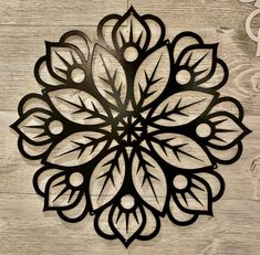 a metal wall hanging on the side of a wooden wall with leaves and circles in it