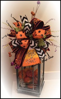 an orange and black bow on top of a lantern