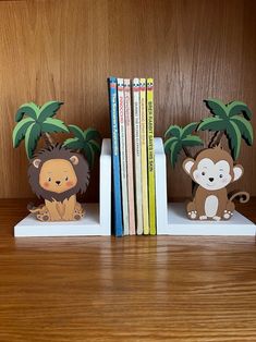 two bookends with animals and palm trees are on a shelf next to books