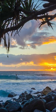 a person riding a surfboard on top of a wave in the ocean at sunset