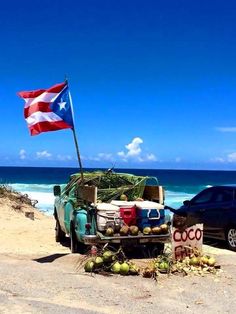 a truck parked on the beach next to an american flag