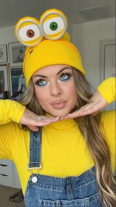 a woman wearing overalls and a yellow hat with googly eyes on her head