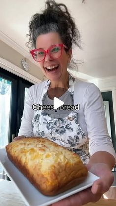 a woman in glasses holding a loaf of bread on a white plate with the words cheese bread