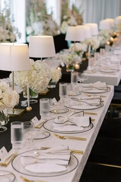 a long table is set with white flowers and place settings for formal dinnereons