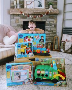 a young boy sitting on the floor with toys in front of him