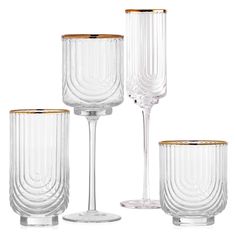 four clear glass vases with gold rims on each one and the other side