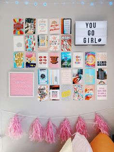 a wall with pictures and pink tassels hanging from it's sides in a bedroom