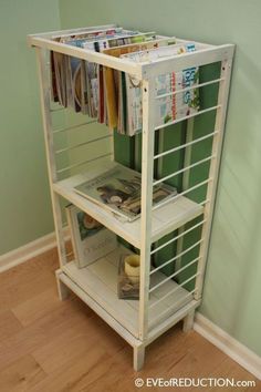 a white shelf with magazines on it next to a green wall and hardwood flooring