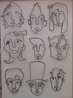 a group of paper cut out of faces on a white sheet with black lines in the middle