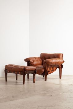 a brown leather chair and ottoman sitting in front of a white wall with no one on it