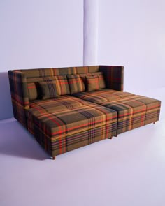 a plaid couch sitting on top of a white floor next to a tall pole in the background