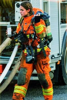 a woman in an orange firefighter's uniform holding a hose and water bottle