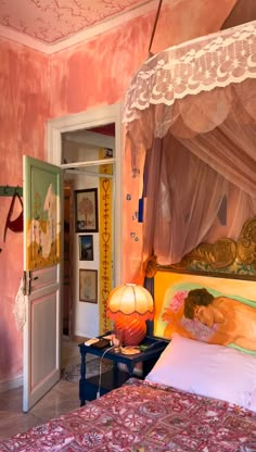 a bedroom with pink walls and an ornate canopy over the headboard, along with a colorful bed spread