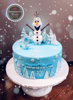 there is a blue frosted cake with a snowman on top