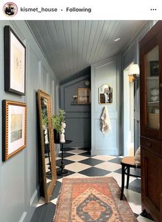 a hallway with a rug, mirror and pictures on the wall in front of it