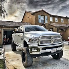 a white ram truck parked in front of a house on a cloudy day with storm clouds