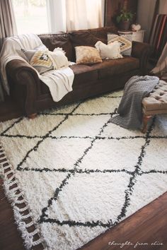 a living room with a brown couch and white rug