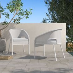 two white chairs sitting next to each other near a tree