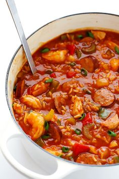 a large pot filled with shrimp and red pepper soup on top of a white table