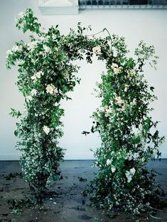 an arch covered in white flowers and greenery