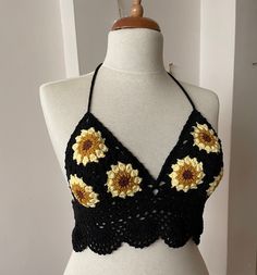 a mannequin wearing a black and yellow crochet halter top with sunflowers on it