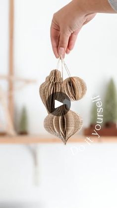 a person is holding two heart shaped ornament hanging from the ceiling in front of a white wall