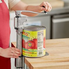 a woman is holding a can opener over a counter