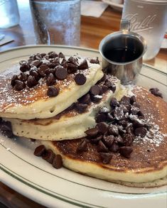 three pancakes with chocolate chips on top and syrup in the middle, sitting on a plate