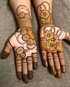 two hands with henna tattoos on them, one has flowers and the other has leaves