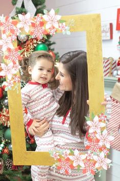 a woman holding a child in front of a christmas tree